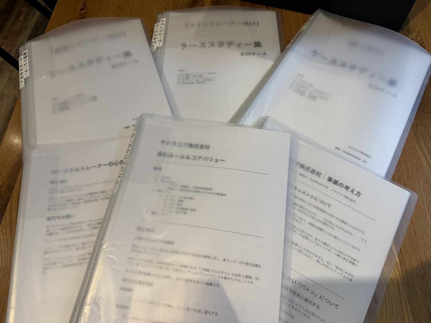 ケーススタディー集や事業の考え方などのトレーナー向け資料ファイルが机に並んでいる